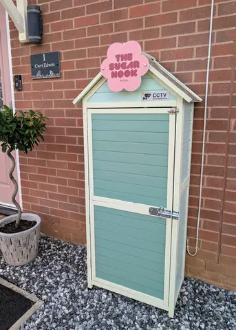 A small blue shed with a pink roof.