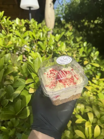 A person holding a piece of cake in a plastic container.