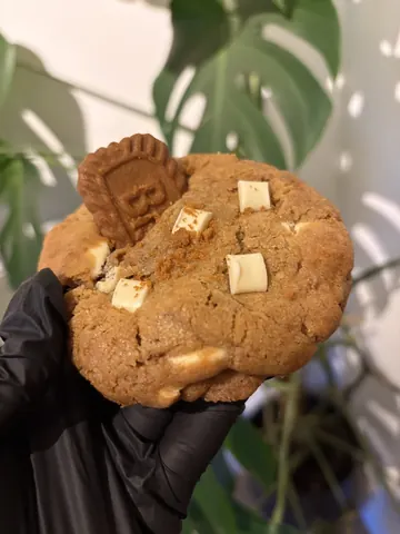 A person is holding a cookie with a picture of a robot on it.
