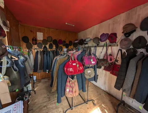 A store with a red ceiling and a rack of purses.