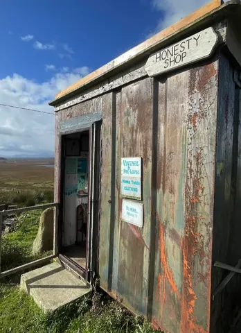 A rusty building with a sign that says Honesty Shop.
