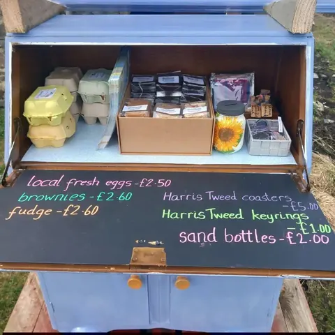 A small wooden box with a sign that says "local fresh eggs" on it.