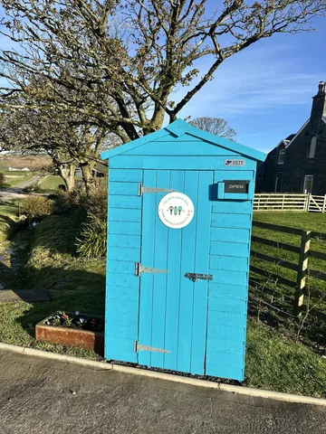 A blue shed with a white door and a sign on it.