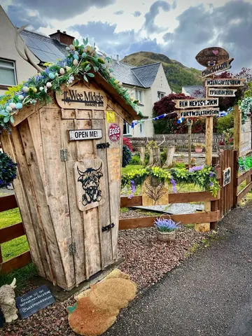 A wooden outhouse with a sign that says "Open me" on it.