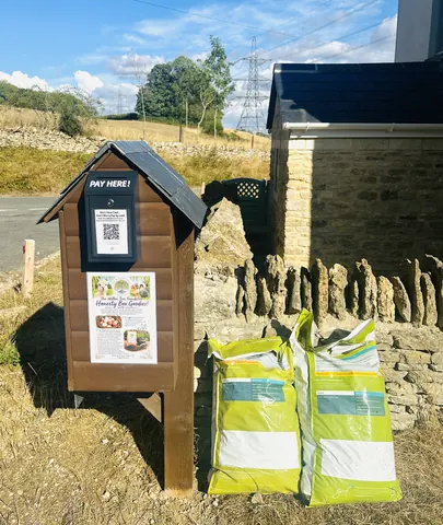 Two bags of mulch are sitting next to a wooden box.