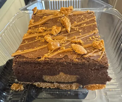 A slice of chocolate cake with nuts on top.
