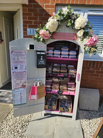 A small pink and white building with a sign that says "The Bake Shop" on it.