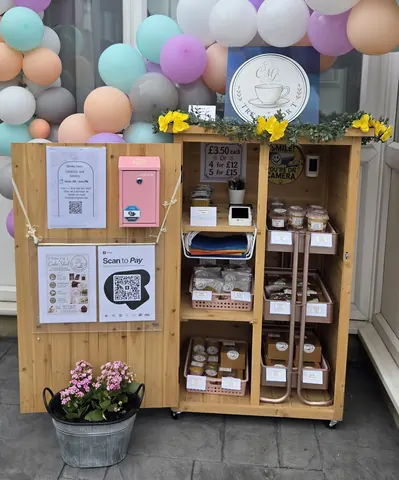A wooden box with a pink door and a sign that says "scan to pay".