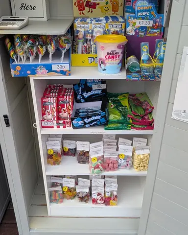 A white shelf with a variety of candy on it.