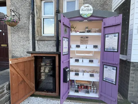 A purple and white food stand with a refrigerator and a shelf.