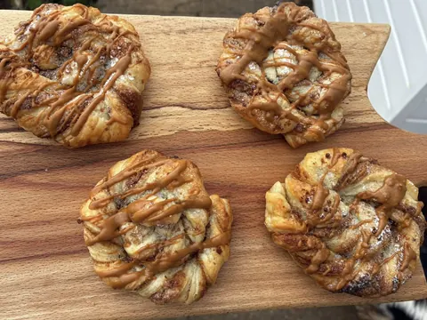 A wooden cutting board with four pastries on it.