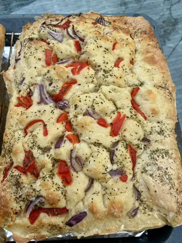 A pizza with red peppers and onions on it.
