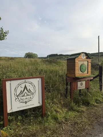 A sign is posted in a field with a tree in the background.