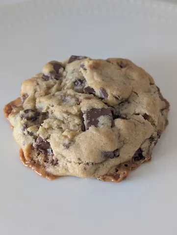 A chocolate chip cookie on a white plate.