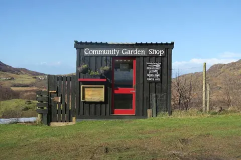 A small building with a red door and a sign that says Community Garden Shop.