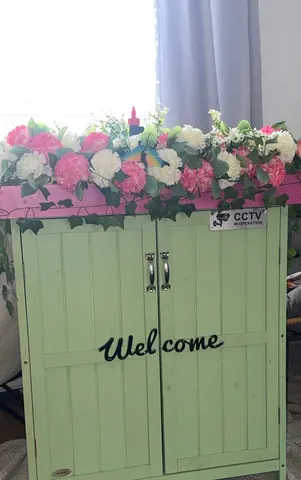A green cabinet with a pink trim and a white sign that says "welcome".