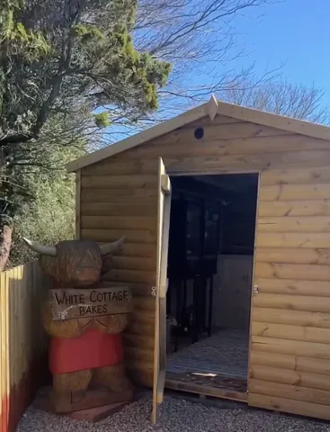 A wooden shed with a sign that says White Cottage Bakes.