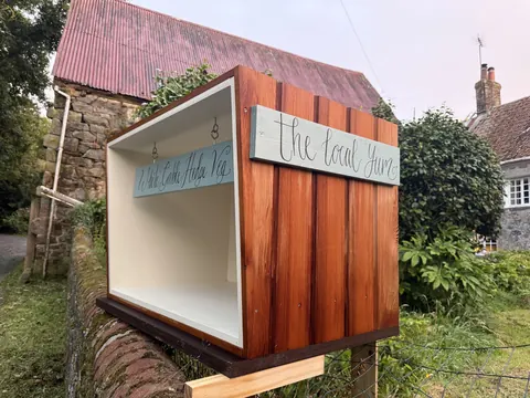A wooden box with a sign on it that says "The Local Hut".