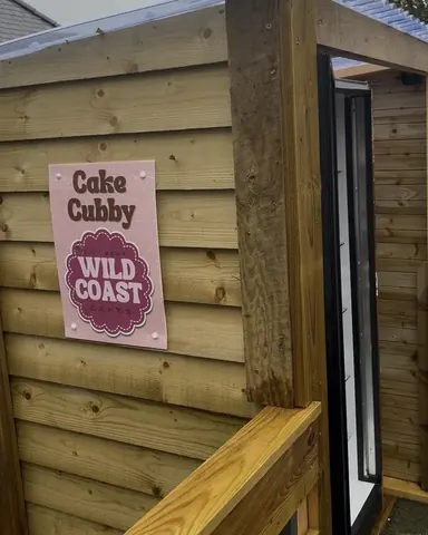 A sign on a wooden wall advertising cake.